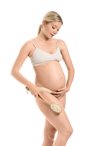 Belle jeune femme enceinte avec brosse de massage sur fond blanc - Photo, image
