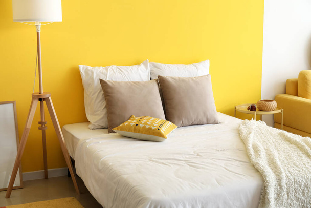Cama confortável e lâmpada de assoalho perto da parede de cor - Foto, Imagem