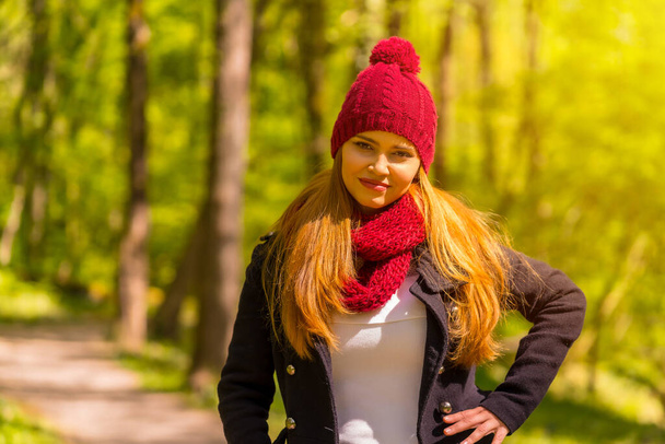 Latin girl with a black jacket, scarf and red woolen hat enjoying in an autumn park, with a little cold in the park - Fotoğraf, Görsel