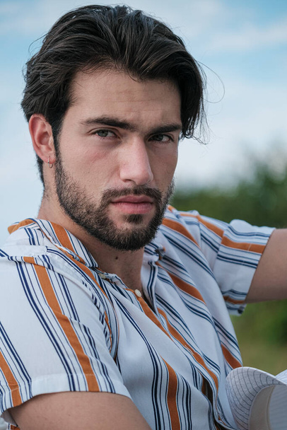πορτρέτο του όμορφου μελαχρινού ιταλικού μοντέλου με ανοιχτόχρωμα μάτια και ριγέ πουκάμισο με γενειάδα. Υψηλής ποιότητας φωτογραφία - Φωτογραφία, εικόνα