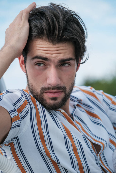 ritratto di un bellissimo modello italiano dai capelli scuri con occhi chiari e camicia a righe con barba. Foto di alta qualità - Foto, immagini