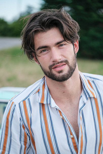 portrait of beautiful dark-haired italian model with light eyes and striped shirt with beard . High quality photo - Photo, Image