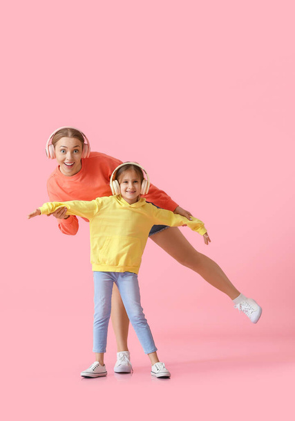 Jeune femme et sa petite fille dansant et écoutant de la musique sur fond de couleur - Photo, image
