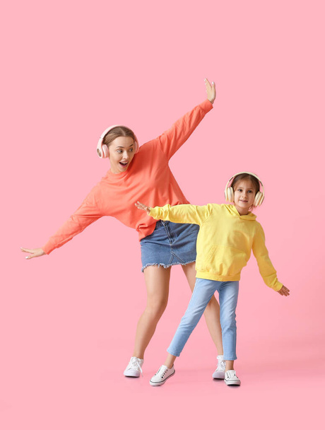 Nuori nainen ja hänen pieni tyttärensä tanssivat ja kuuntelivat musiikkia väritaustalla - Valokuva, kuva