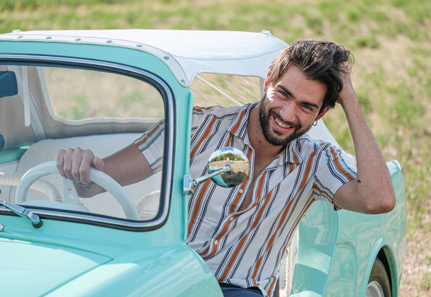 portrait d'un bel homme modèle italien aux cheveux bruns aux yeux clairs avec barbe dans une vieille voiture italienne tiffany. Photo de haute qualité - Photo, image
