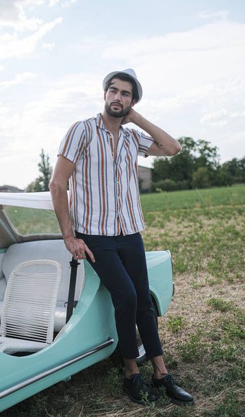 portrait of beautiful dark-haired italian model man with light eyes with beard in an old italian tiffany car. High quality photo - Foto, Imagem