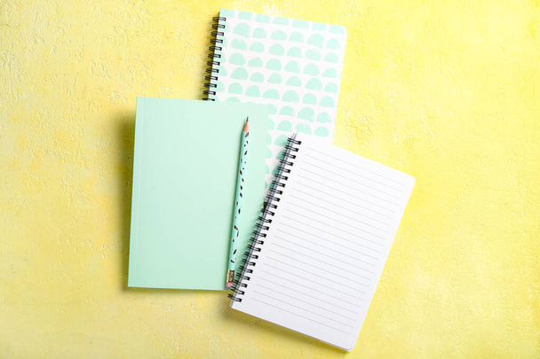 Different notebooks and pencil on color background - Photo, Image