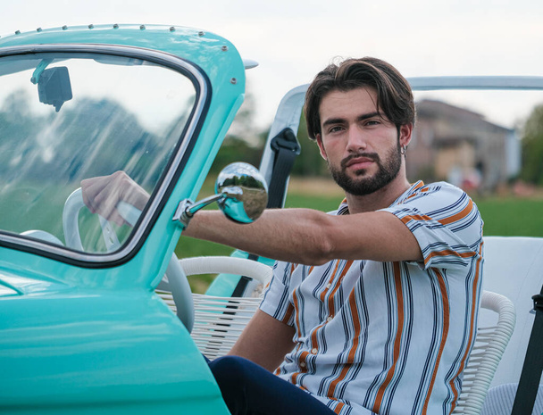 Портрет красивого італійця з темним волоссям з легкими очима з бородою в старому автомобілі італійської тиффани. Фотографія високої якості - Фото, зображення