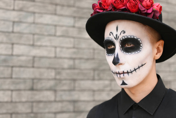 Young man with painted skull on his face outdoors. Celebration of Mexico's Day of the Dead (El Dia de Muertos) - Photo, Image