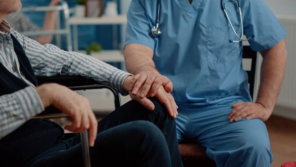 Primer plano de las manos de un enfermero reconfortando a un paciente mayor - Foto, imagen