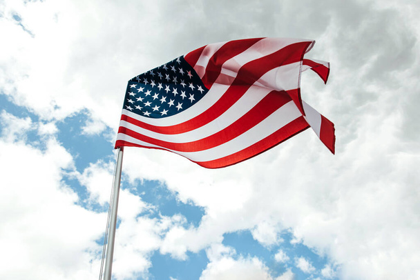 Флаг США, размахивающий ветром над облачным небом. - Фото, изображение