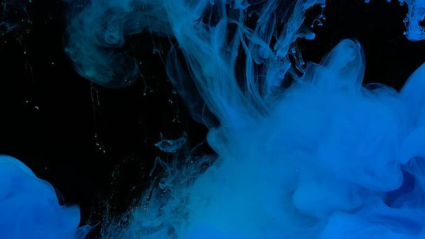 Beautiful abstract background. Blue watercolor ink in water on a black background. Waves and drops of blue paint. Blue cloud of ink. Cosmic magic background. - Фото, изображение