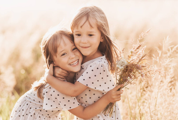Kaksi pientä onnellista identtistä kaksosta leikkimässä yhdessä luonnossa kesällä. Tytöt ystävyys ja nuoruus käsite. Aktiivinen lasten elämäntapa. - Valokuva, kuva