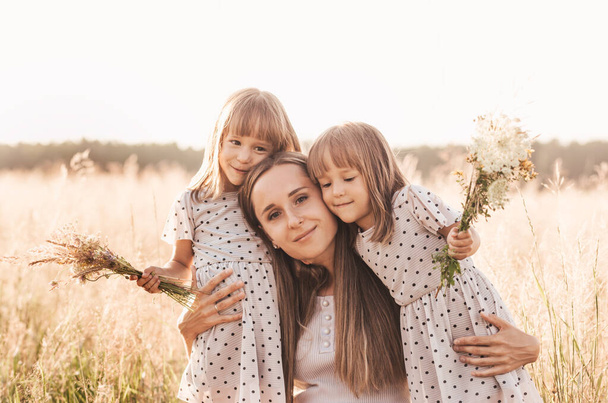 Mamá con dos niñas gemelas jugando en la naturaleza en el verano - Foto, imagen
