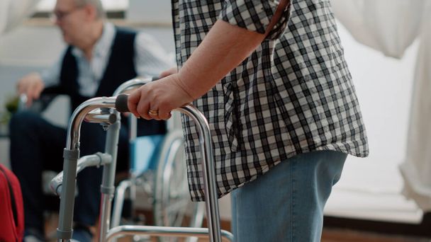 Κοντινό πλάνο του ηλικιωμένου ασθενούς με αναπηρία χρησιμοποιώντας πλαίσιο περιπάτου - Φωτογραφία, εικόνα