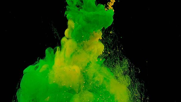 Green and yellow cloud of ink. Beautiful abstract background. Green and yellow watercolor ink in water on a black background. Waves and drops of green and yellow colors. Cosmic magic background. - Zdjęcie, obraz
