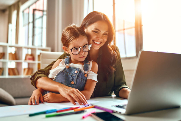 Business woman and mom working with her little daughter at a laptop. Freelance, work from home. - Photo, Image