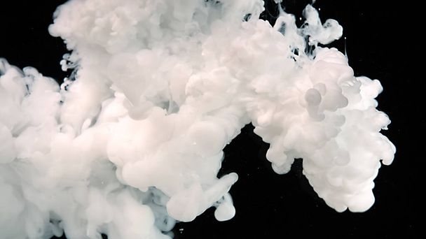 White cloud of ink on a black background. Meditative magic abstract background. Black and white art. White watercolor ink in water on a black background. White watercolor paints in water. - Foto, afbeelding