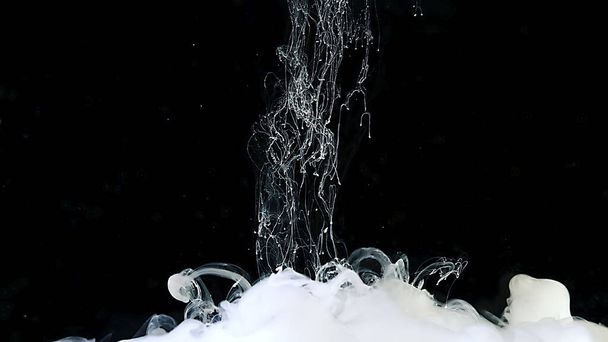 Drops of white ink in water. White abstract background. White watercolor ink in water on a black background. - Foto, afbeelding