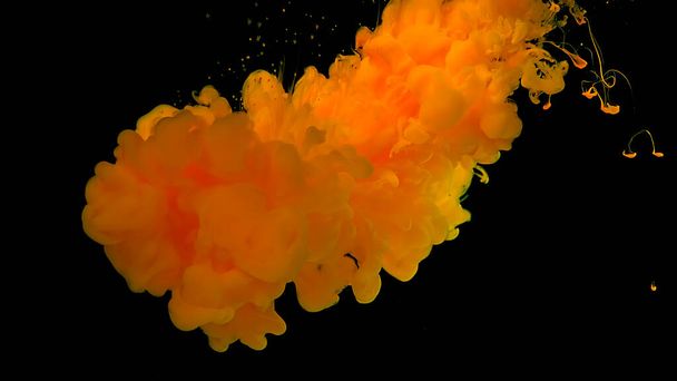 Yellow watercolor ink in water on a black background. Waves and drops of yellow colors. Cosmic magic background. Yellow cloud of ink. Beautiful abstract background. - Photo, image