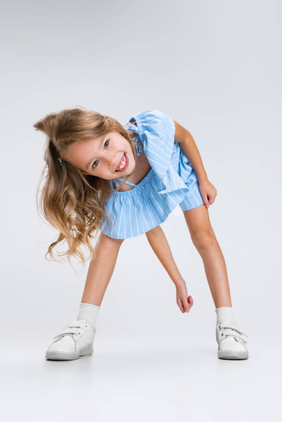 Full-length portrait of smiling girl in casual clothes having fun isolated on white studio background. Happy childhood concept. Sunny child. Looks happy, delighted - Foto, immagini