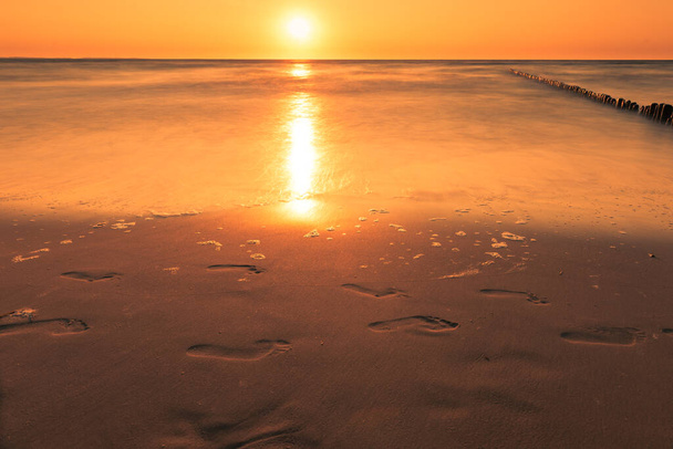 Mar Báltico en la hermosa puesta de sol en la playa de Miedzyzdroje, ciudad donde se celebra el festival de las estrellas cada año. Costa báltica polaca. Ciudad famosa entre los turistas. Muelle al atardecer - Foto, Imagen