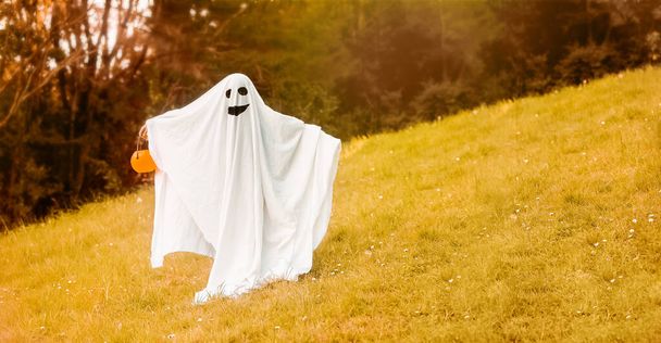 ребенок одет как призрак на Хэллоуин, детский костюм призрака, открытая съемка, естественный фон - Фото, изображение