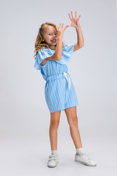 Full-length portrait of smiling girl in casual clothes having fun isolated on white studio background. Happy childhood concept. Sunny child. Looks happy, delighted - Φωτογραφία, εικόνα