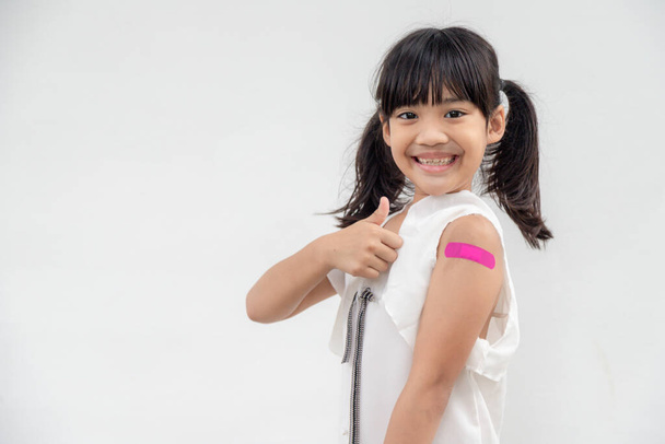 Asiatisches kleines Mädchen, das seinen Arm zeigt, nachdem es geimpft oder geimpft wurde, Kinderimpfung, Covid Delta Impfkonzept - Foto, Bild