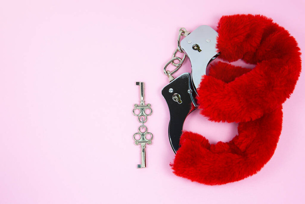 Menottes moelleuses sexy rouge avec des clés sur un fond rose. - Photo, image
