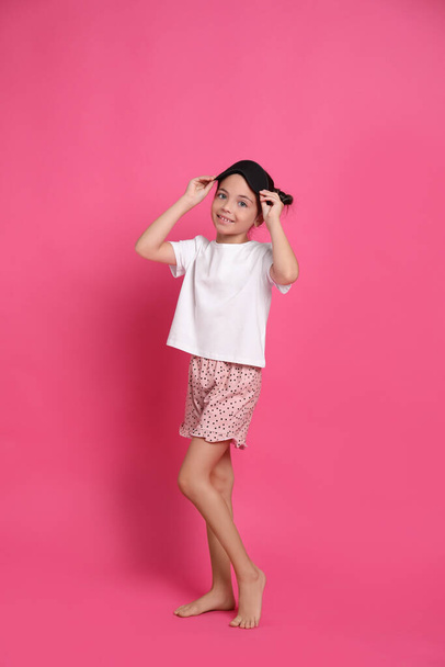 Cute girl in pajamas with sleep mask on pink background - Fotografie, Obrázek