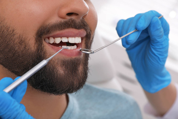 Dentist examining young man's teeth in clinic, closeup - Photo, Image