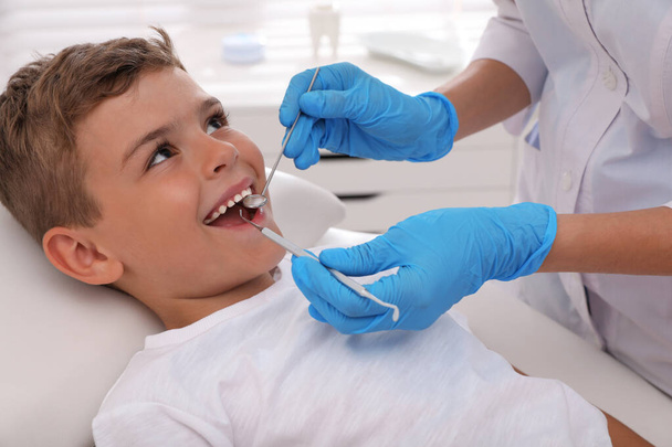 Dentist examining little boy's teeth in modern clinic - 写真・画像