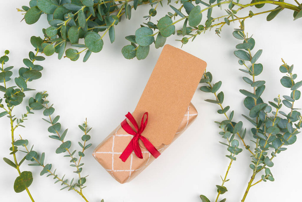 Gift boxes packed in craft paper with simple decor of green plant branches - Fotoğraf, Görsel