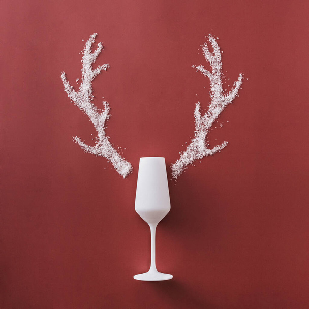 Fondo navideño festivo con elegante champán blanco y astas formadas de nieve de invierno sobre un fondo rojo cuadrado con espacio para un saludo estacional - Foto, Imagen