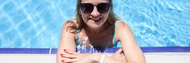 Young woman in sunglasses lying on side of pool - Fotoğraf, Görsel