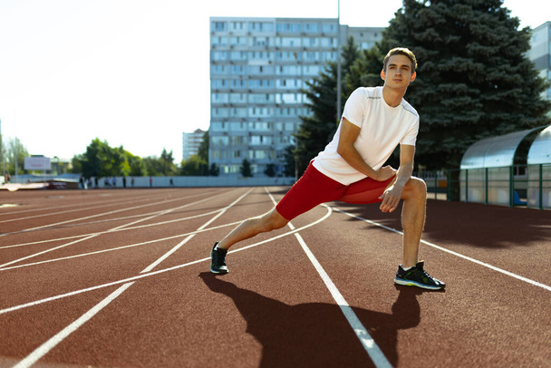 Young Caucasian sportive man, male athlete, runner practicing alone at public stadium, sport court or running track outdoors. Summer sport games. - Photo, image