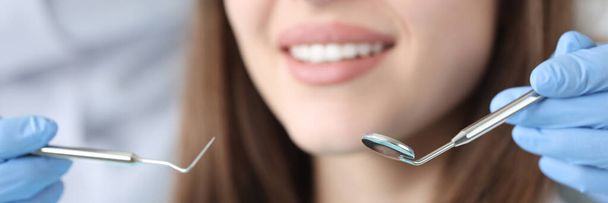 Zubní lékař drží zubní nástroje před pacientkou na klinice detailní záběr - Fotografie, Obrázek