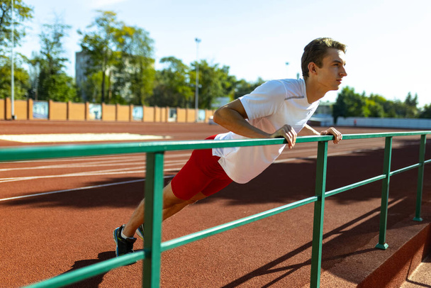 One Caucasian sportive man, male athlete, runner workouts alone at public stadium, sport court or running track outdoors. Summer sport games. - Fotografie, Obrázek