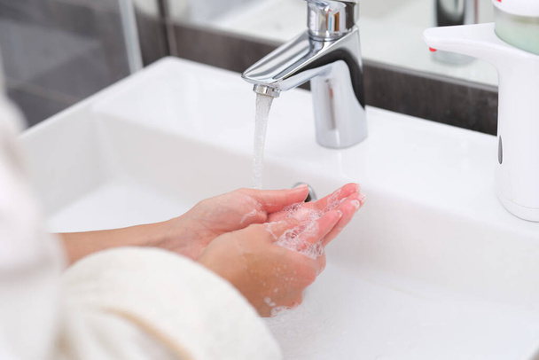 Mujer lavándose las manos bajo el agua del grifo en el baño de cerca - Foto, Imagen
