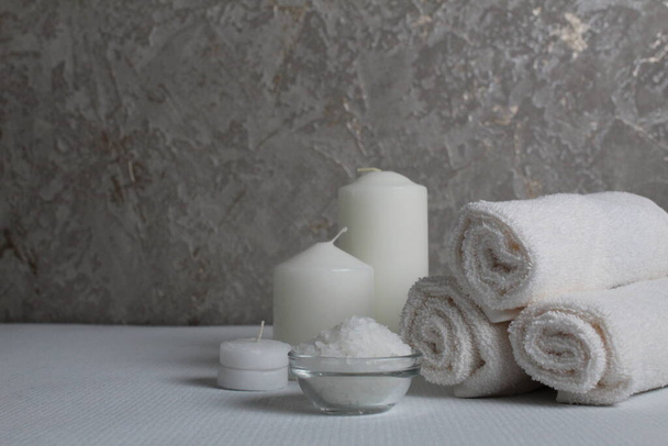 Spa treatments care home body llax massage. White candle towels in a roll of salt and scrub on a gray background with space for copyspace text. Beauty parlour. - Photo, Image