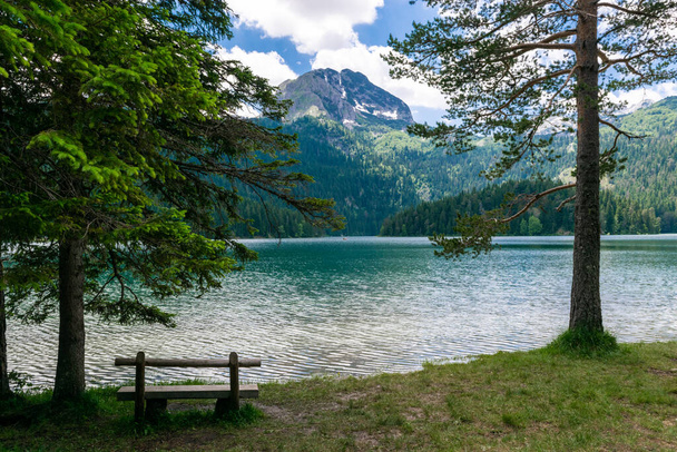 Wooden bench near Glacial Black Lake. Premium tourist attraction of Durmitor National Park. Walking path circles around lake, and is popular destination for recreation and hiking. Montenegro - Fotografie, Obrázek