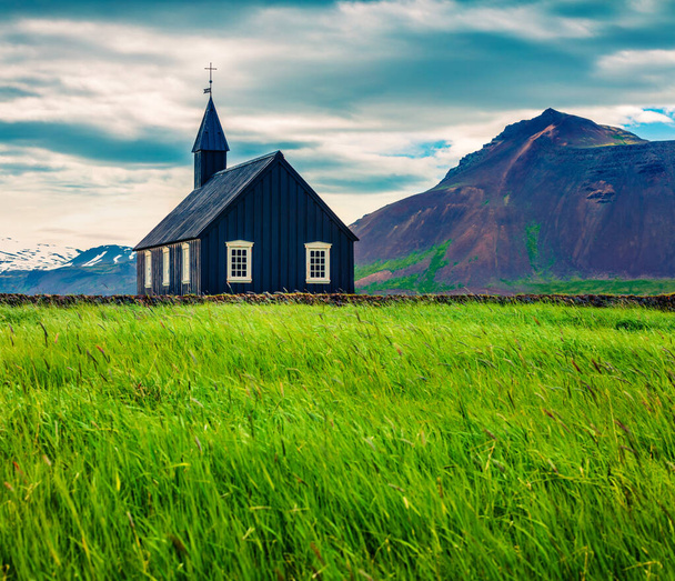 Black wooden Budakirkja church at Saefellsnes. Dramatic summer morning with field of fresh green grass on Snafellsnes peninsula, western Iceland, Europe. Artistic style post processed photo. - Photo, Image