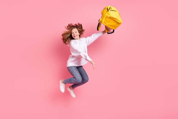 Full length body size view of pretty cheerful trendy girl jumping throwing bag having fun isolated over pink pastel color background - Фото, изображение