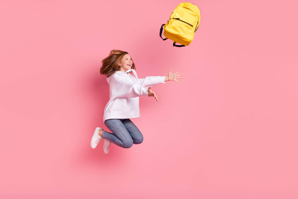 Photo of impressed funky small schoolgirl dressed white sweatshirt jumping throwing rucksack isolated pink color background - Foto, Imagem