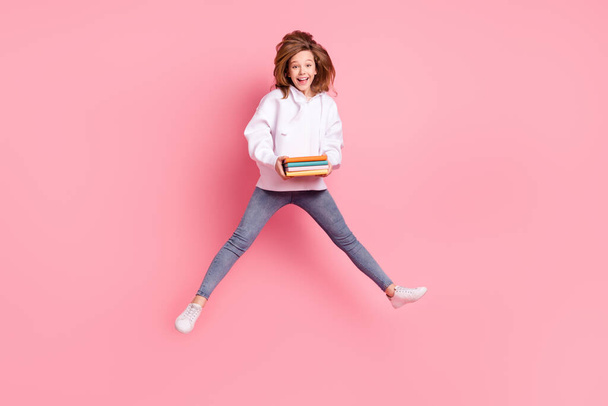 Full length body size back view girl jumping high keeping book stack laughing isolated pastel pink color background - Φωτογραφία, εικόνα