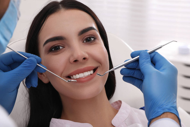 Dentist examining young woman's teeth in modern clinic - 写真・画像