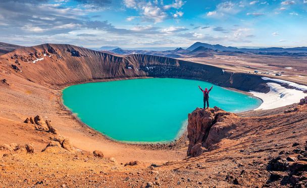 Tourist στέκεται στην άκρη του γκρεμού στη λίμνη Krafla Viti Crater με υψωμένα χέρια και απολαμβάνοντας το πρωί. Ηλιόλουστη καλοκαιρινή σκηνή της Ισλανδίας, Ευρώπη. Ταξιδιωτικός τρόπος ζωής φόντο έννοια - Φωτογραφία, εικόνα