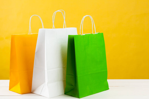 Paper shopping bags on bright yellow background - Foto, Imagen