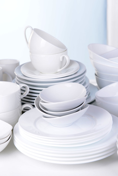 Set of white dishes on table on light background - 写真・画像